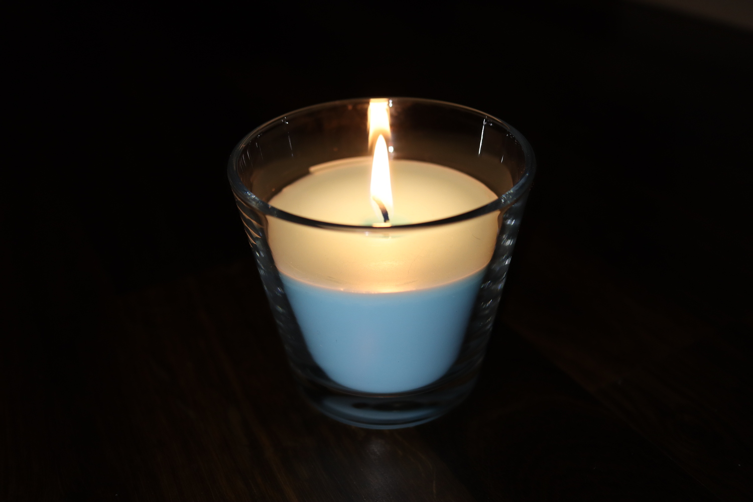 A blue candle lit in a darkened room