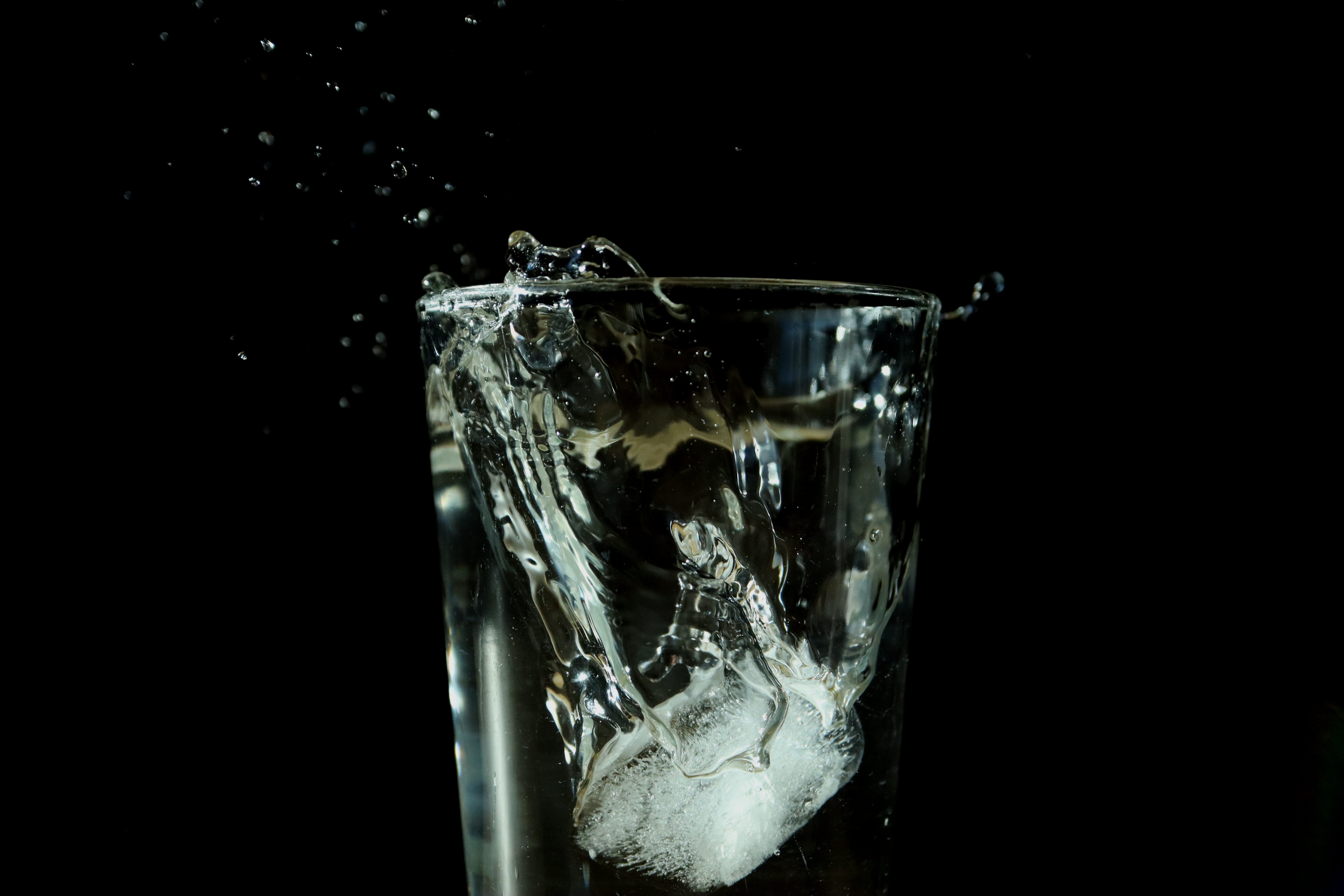 Ice dropped into a glass of water